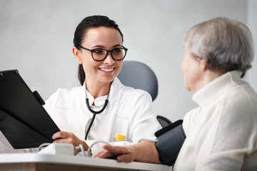 Fototapeta premium healthcare in hospital. smiling female doctor with clipboard consulting senior lady patient after treatment in medical clinic cabinet