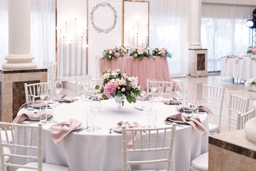 The luxurious round table for the wedding lunch is decorated with flowers and stylish dishes. Beautifully organized event - served festive tables ready for guests
