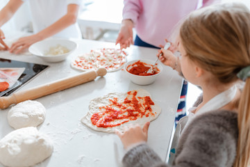 children making pizza at home in kitchen 