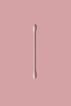 a thin cotton swab for make-up remove on pink background