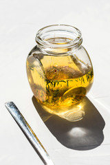 Photo of a glass bottle with fresh organic eco olive oil with herbs healthy fat sunglight on white background