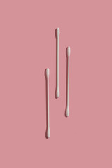 three thin cotton swabs on pink background top view from above