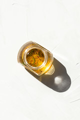 Photo of a glass bottle with fresh organic eco olive oil with herbs healthy fat sunglight on white background