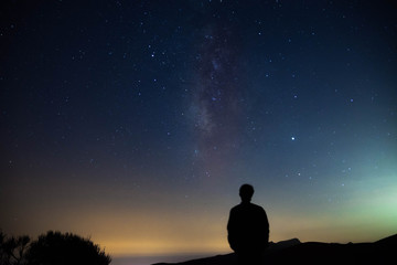 Naklejka na ściany i meble Blurred silhouette of a man observing the starry sky with the milky way