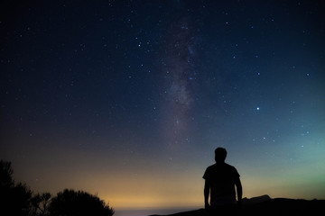 Blurred silhouette of a man observing the starry sky with the milky way