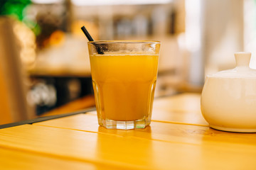 Glass of orange juice on a wooden table. White sugar bowl and a glass of fruit juice. Fresh healthy juice in a glass on a table in a cafe