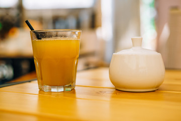 Glass of orange juice on a wooden table. White sugar bowl and a glass of fruit juice. Fresh healthy juice in a glass on a table in a cafe