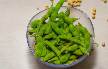 Bowls with soy beans and pods (glycine max) on light background