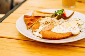 Helpful appetizing breakfast on a white plate. Scrambled eggs with vegetables and croutons in a cafe. Breakfast in the cafe: scrambled eggs, sausages and toast