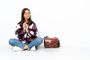 Young student woman sitting on the floor scheming something