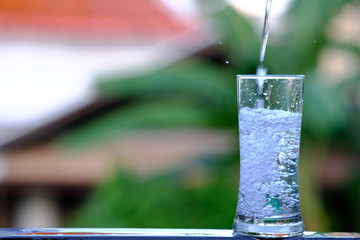 Close up pouring purified fresh drink water from the bottle on wood counter and space for text