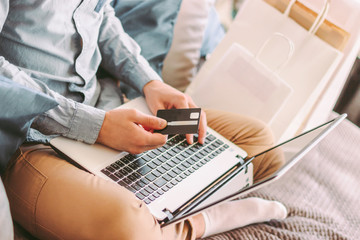 Closeup man shopper hold credit card in hand, typing on laptop keyboard, shopping online from home....