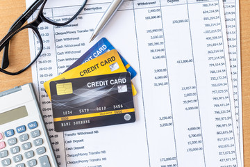 Calculator and Pen on Bank statement and credit card on a Wooden table