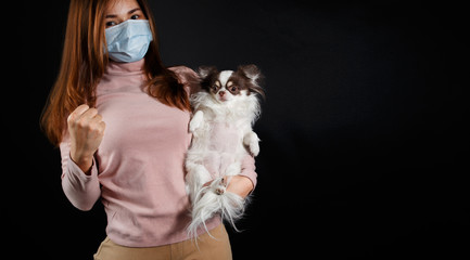 Woman wearing face mask and hoding a dog.