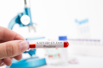 Test tube with a positive COVID-19 test on a white background