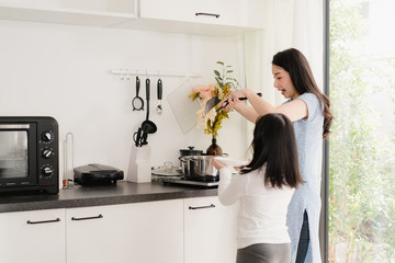 Young Asian Japanese Mom and Daughter cooking at home. Lifestyle women happy making pasta and spaghetti together for breakfast meal in modern kitchen at house in the morning concept.