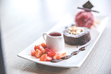 Close up the chocolate lava dessert with strawberry ice cream on white plate.