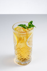 Cold lemonade drink with orange and mint in tall glass