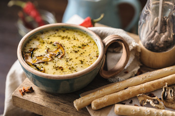 cream soup with mushrooms in a beautiful serving with bread sticks