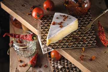 cream cheese brie beautiful serving on a wooden stand with cherry tomatoes and chili