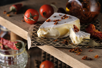 cream cheese brie beautiful serving on a wooden stand with cherry tomatoes and chili