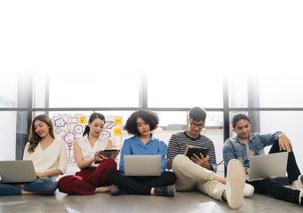 Group of young happy Asian creative business people or hipster student using electronic devices tablet and laptop connection together in modern office. Creative lifestyle young people concept