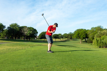 Man teeing off in the tee box, playing golf