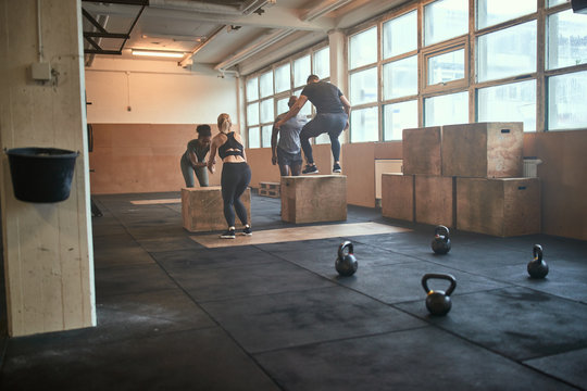 Diverse group of fit people doing box jumps together