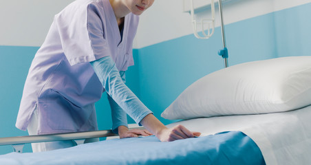 Expert young nurse making the bed at the hospital