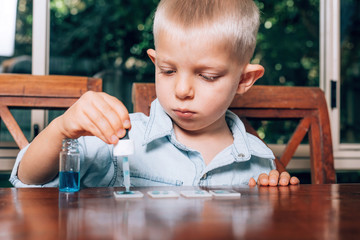 Little boy doing the experimental laboratory activity with colored water and pieces of glass....