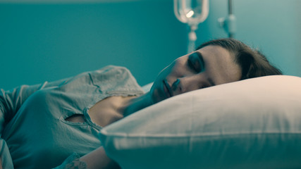 Woman lying in the hospital bed and sleeping with IV drip