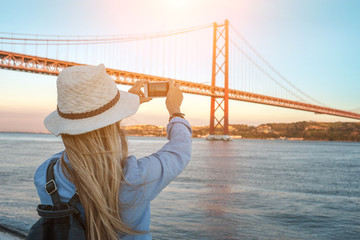 Young traveler woman with smartphone takes pictures in Lisbon 