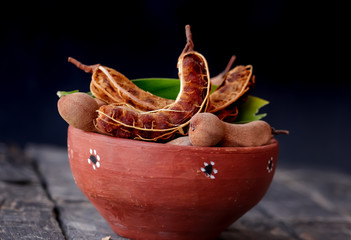 fresh sweet ripe tamarind with leaf, healthy fruit,tamarind fruits and green leaves on red bowl,organic tamarind nature,
