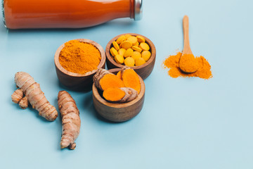 Turmeric in different states: fresh in bottle, pills, powder and cut plant on wooden tray, dry root...