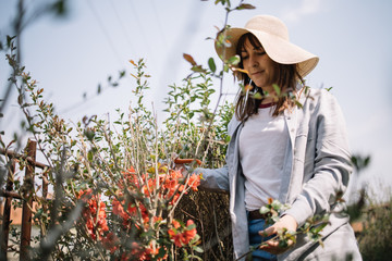 Young woman standing in garden next to blossomed bushes