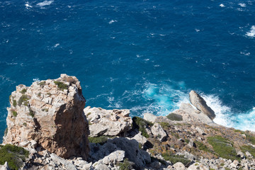 Waves crashing onto barren rocks at the Aegean sea, Greece.  A view from the old town on the remote but beautiful Greek island of Folegandros. The settlement is perched high on steep cliffs.