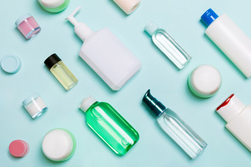 Top view of different cosmetic bottles and container for cosmetics on blue background. Flat lay composition with copy space