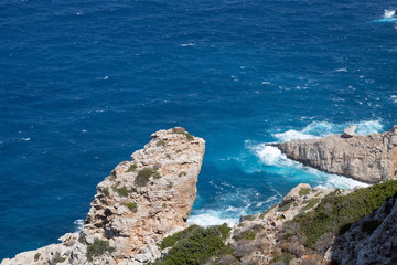 Craggy rocks with sea waves crashing at the edge of the sea at the remote Greek island of...