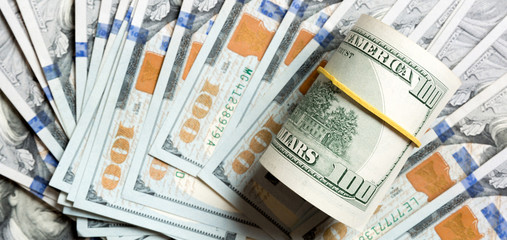 Top view of 100 rolled dollar bills on background made with one hundred dollar banknotes. Business concept
