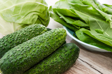 green vegetables on a wooden table. Cabbage, cucumbers and sorrel. Close-up.