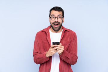 Young caucasian man wearing corduroy jacket over blue background surprised and sending a message