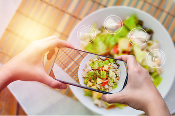 Top view 
woman uses the application on the phone to calculate the nutrients in the salad bowl in the morning for good health. Healthy food concept.