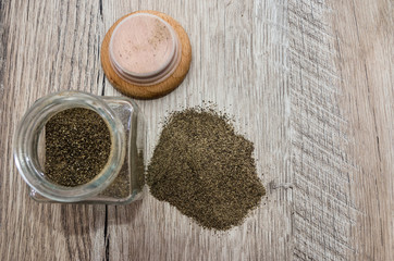 ground pepper in a glass jar on a wooden background.