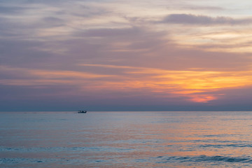 Obraz premium Orange sunrise with a boat in the distance