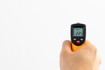 Contactless thermometer measuring with white background and copyspace area. Check temperature and control tools and equipment for preventing flu spreading. Orange contactless thermometer