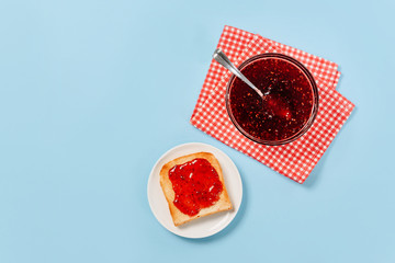 Bread toast and raspberry jam isolated on a blue background with a copy space