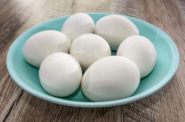 white chicken eggs in a plate on a wooden background. Close-up.