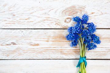Bouquet of muscari flowers on a light wooden table. Country style.