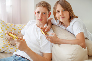 Children teenagers play a game on the phone at home.