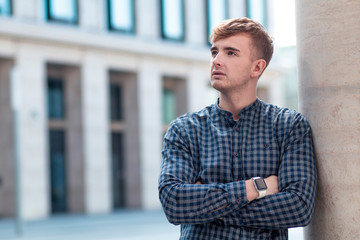Fototapeta premium Sad pensive thoughtful guy, young handsome man in shirt thinking about future, dreaming or planning outdoors, looking up with hands, arms crossed. Copy space